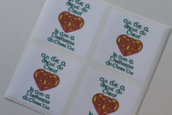 Stickers on paper backing that read "An áit a bhfuil do chroí, is ann a thabharfas do chosa thú" with a snaidhm Cheilteach/Celtic knot design heart